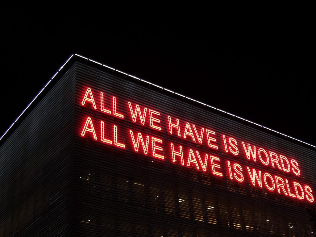 Néons avec la citation "All we have is words, all we have is worlds"