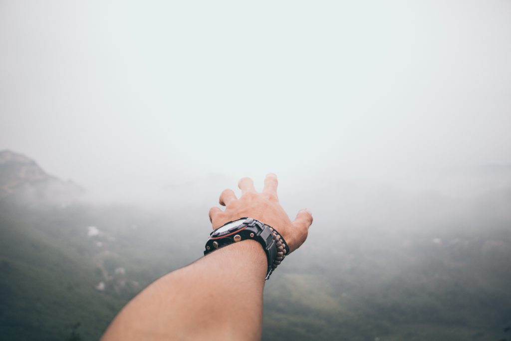 Main d'homme avec montre et bracelets tendus vers le paysage