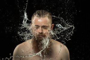 Homme en train de secouer ses cheveux et sa barbe pleins d'eau