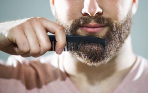 Homme en train de passer un peigne dans sa barbe pour gagner en volume