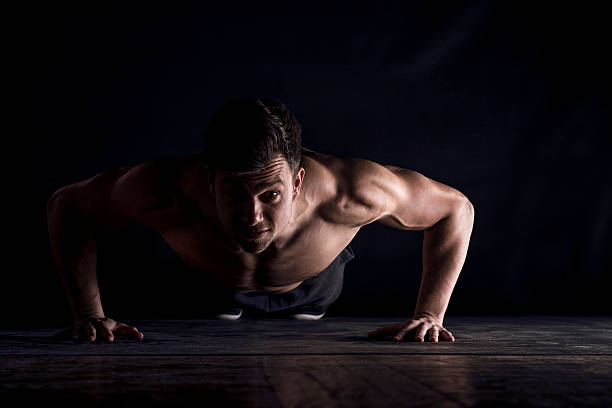 Jeune homme en position de gainage sur fond noir