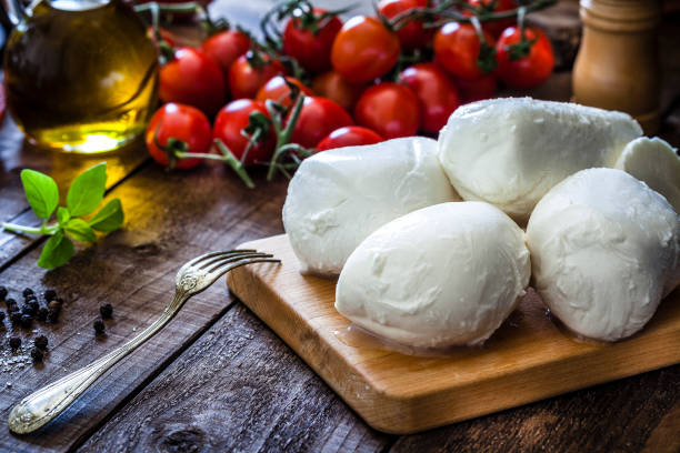 Planche en bois de cuisine avec boules de mozzarella et grappes de tomates dans le fond