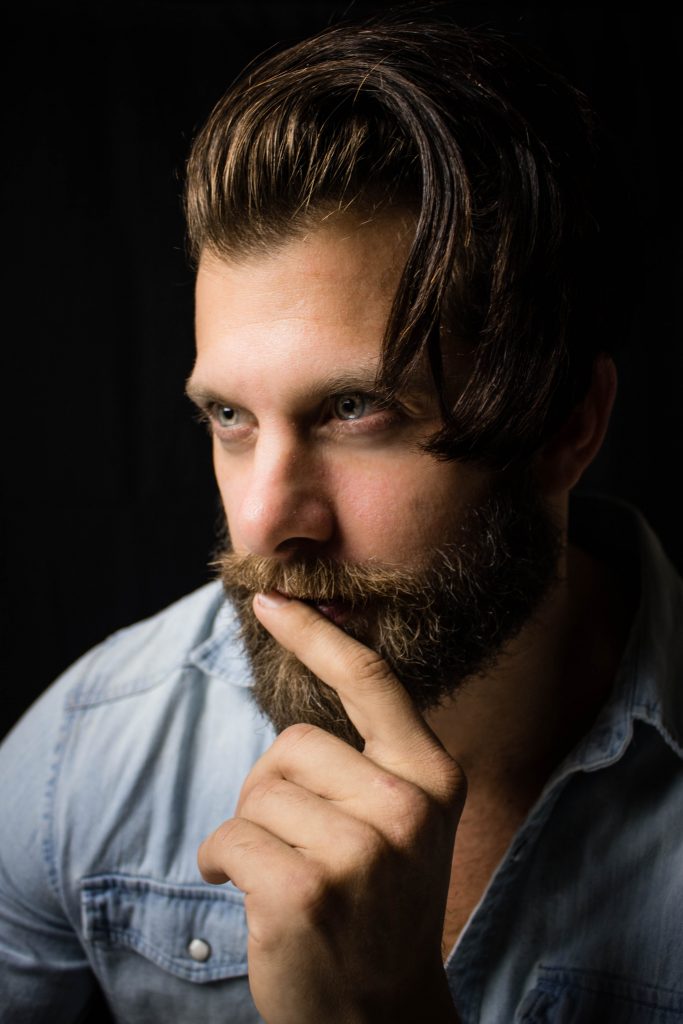 Homme avec une barbe bien fournie qui se tient le menton dans la main