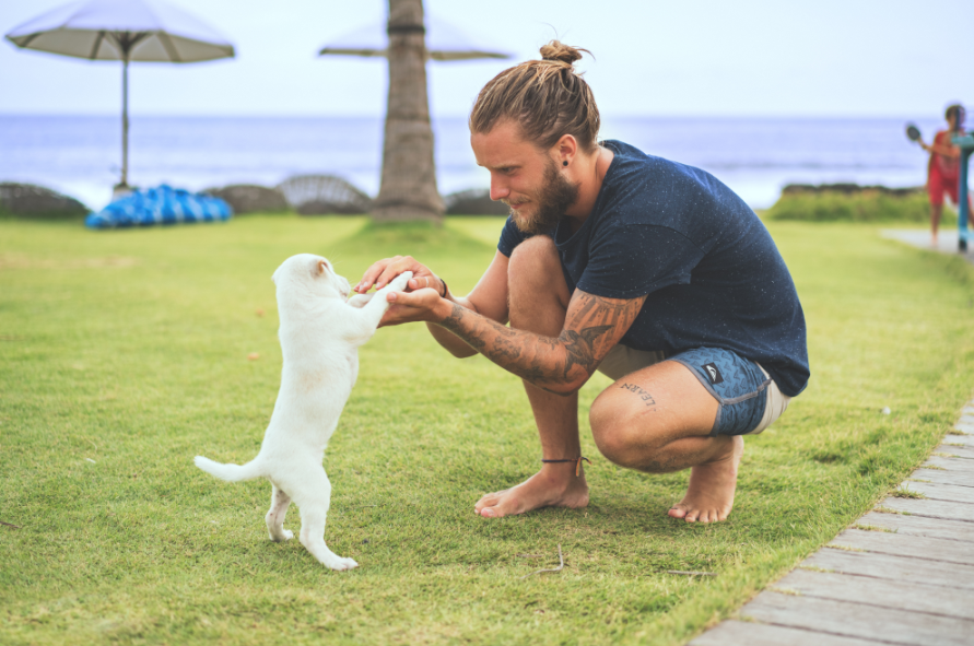 Homme avec un chignon qui caresse un chiot