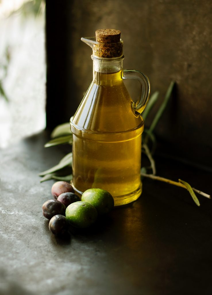 Bouteille d'huile d'olive sur une table, avec une branche d'olivier