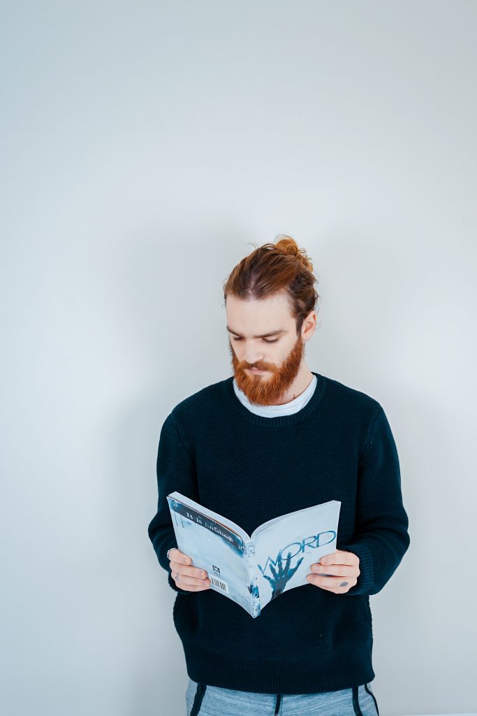 Homme roux avec un man bun qui lit un livre