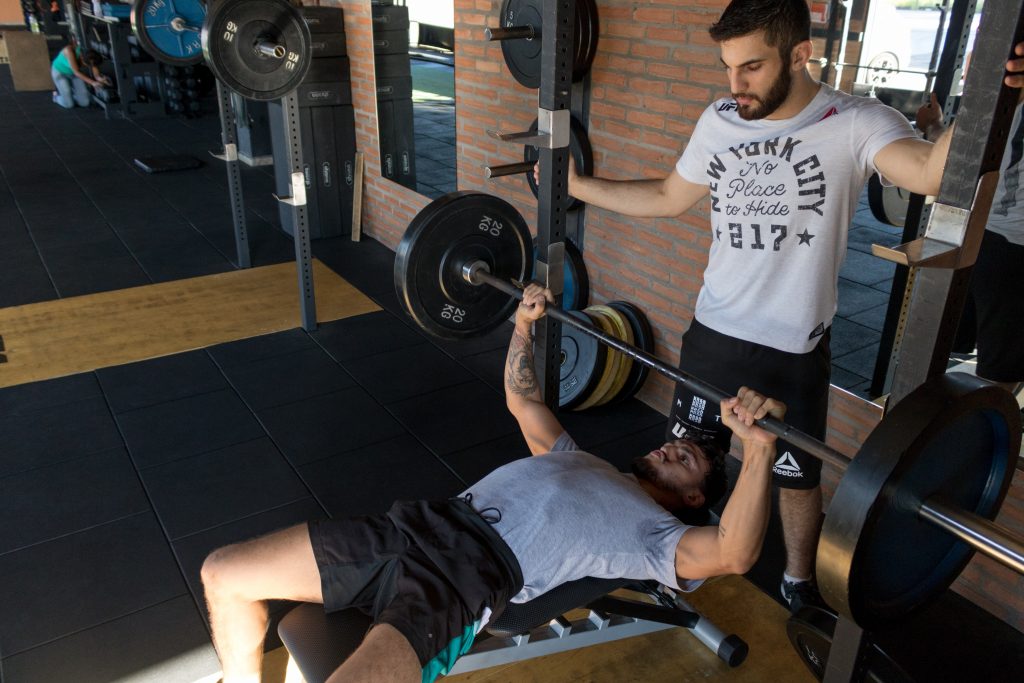 Coach sportif qui entraine un homme dans une salle de sport