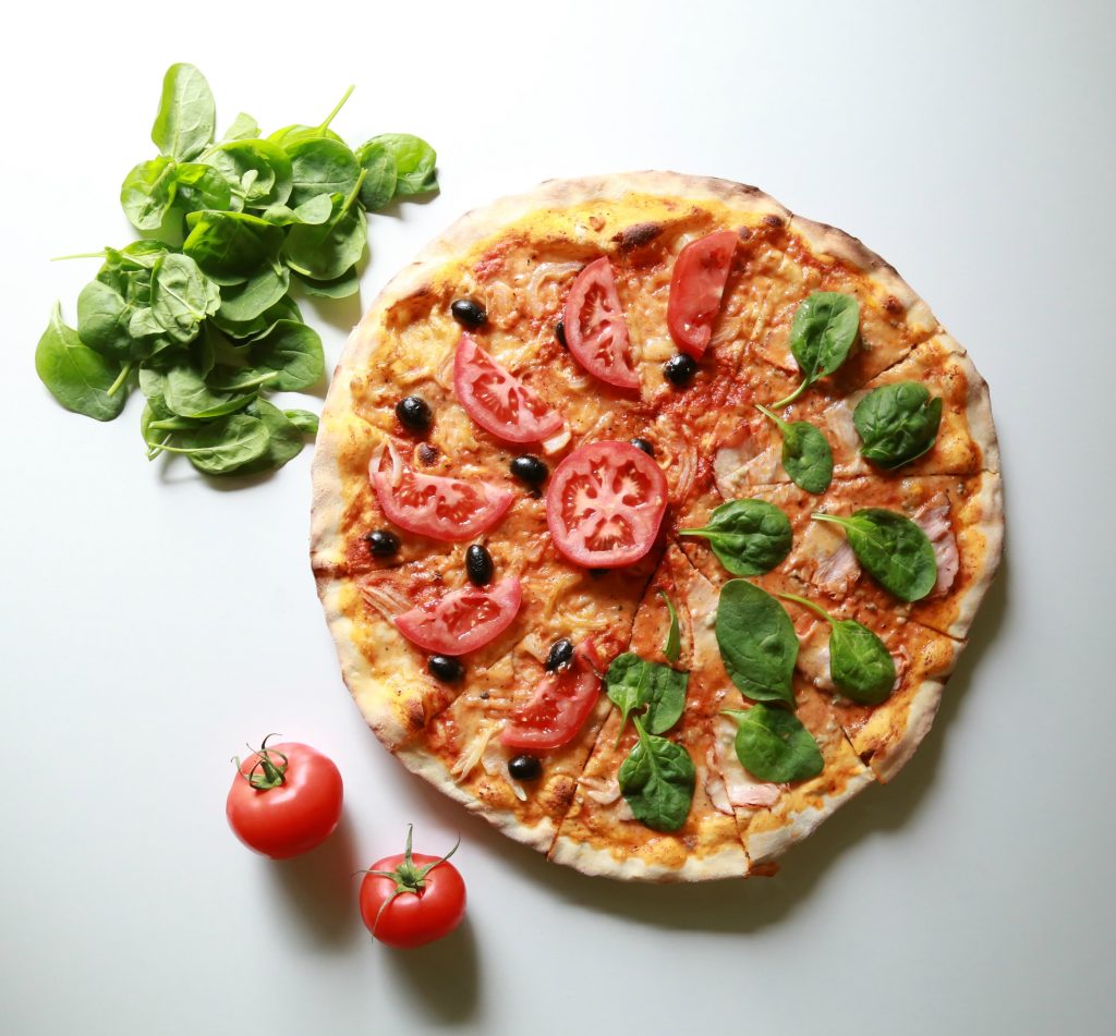 Pizza avec des tomates, des olives et du basilic