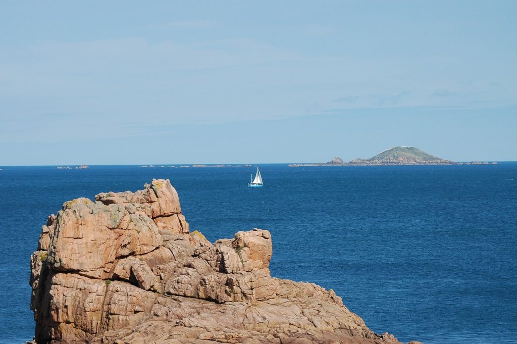 littoral breton avec un rocher au premier plan et un voilier en arrière-plan