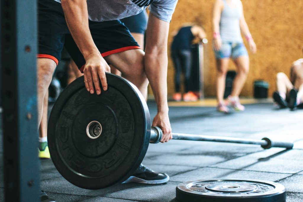 Homme qui met des poids sur des haltères dans sa salle de sport